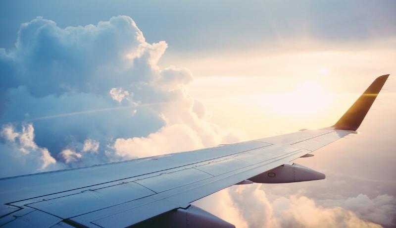 Airplane wing over clouds at sunset